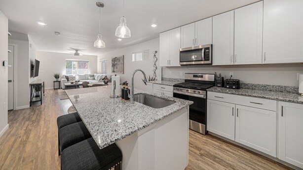 A modern kitchen with white cabinets, granite countertops, stainless steel appliances, and a central island with seating. - Hummingbird Haven-Prime location in South Longmont-sleeps 8,4beds,blocks to Rec (Longmont)