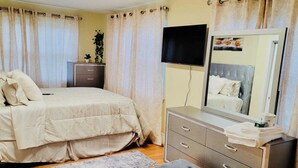 Ein Schlafzimmer mit einem Bett, einem Schminktisch, einem Spiegel und einem Fernseher.