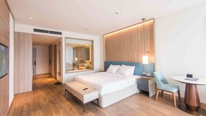 Ein modernes Hotelzimmer mit einem großen Bett, Nachttischen, einem Schreibtisch mit Stuhl und einem kleinen runden Tisch.