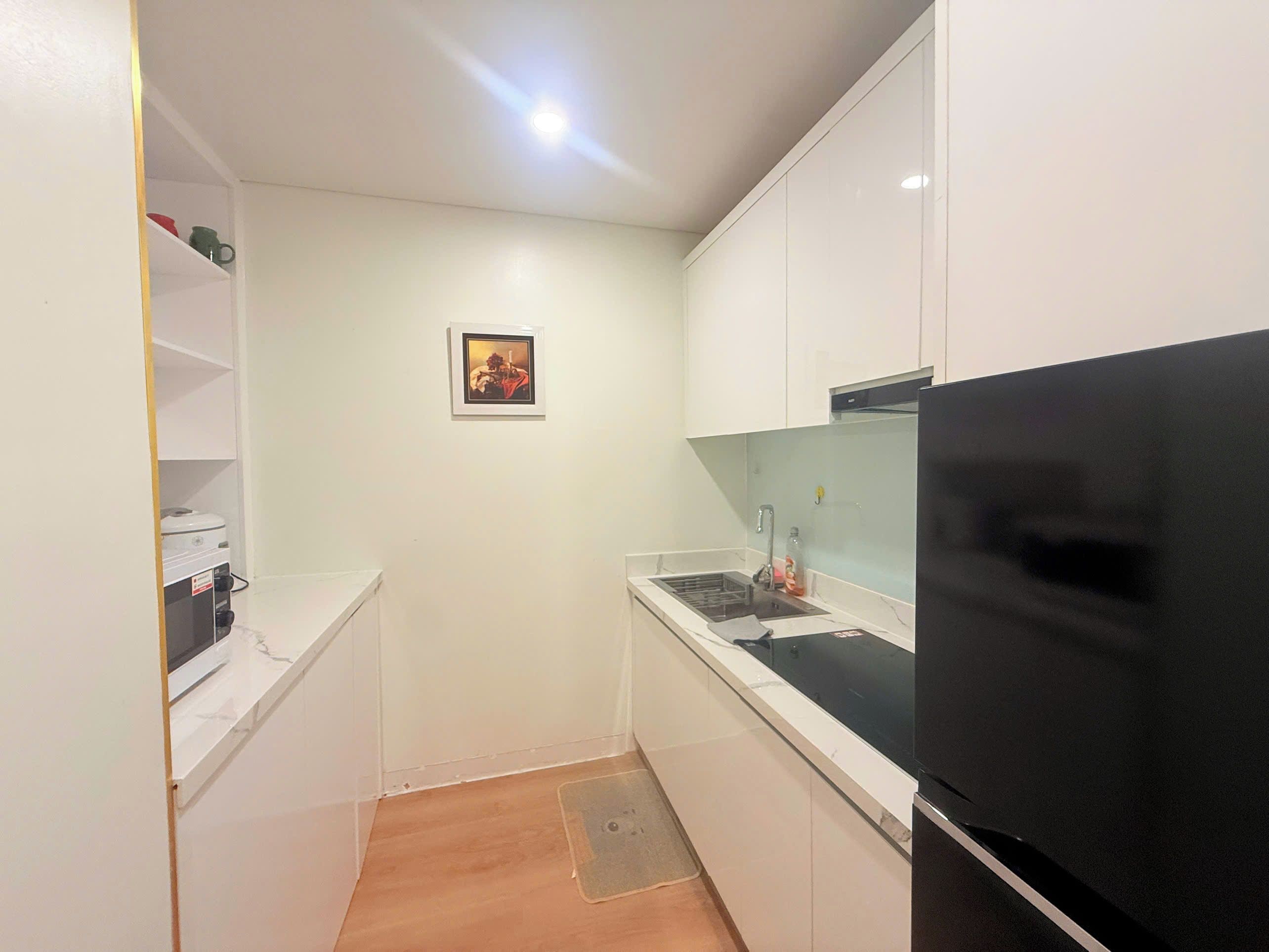 A compact kitchen with white cabinets, a black refrigerator, and a small countertop.