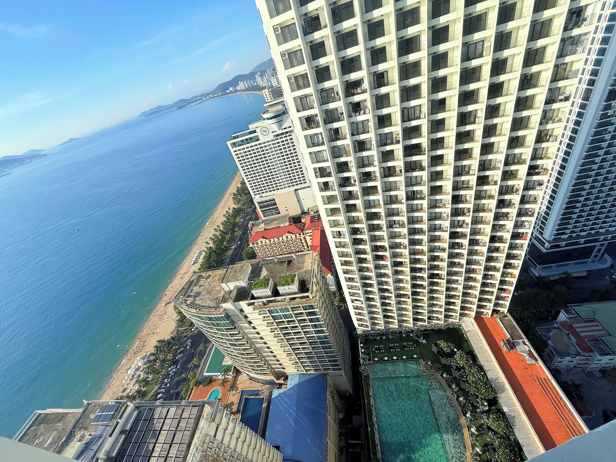 Un edificio de gran altura con múltiples balcones que dan a una playa y al mar.