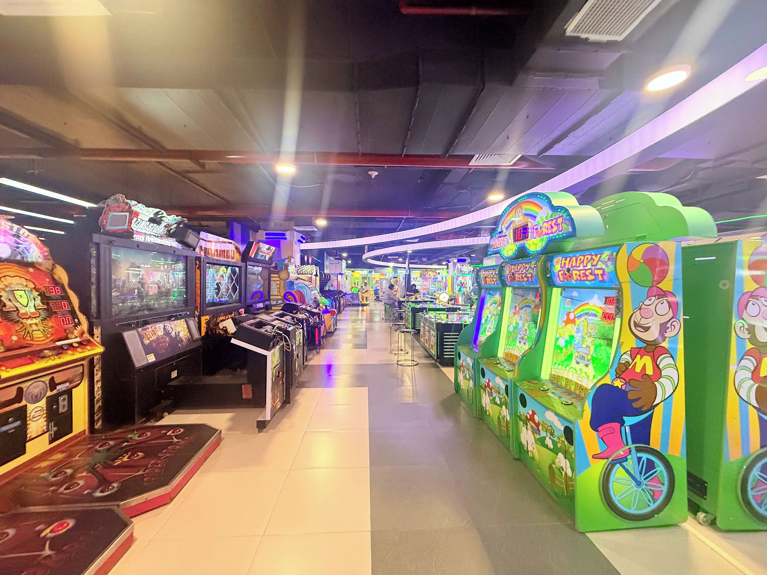 An indoor arcade with various gaming machines and a clear walkway.