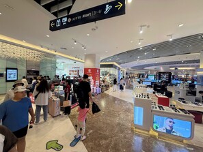 Interior d'un centre comercial amb diverses botigues, incloent un aparador de sabates i un terminal de punt de venda.