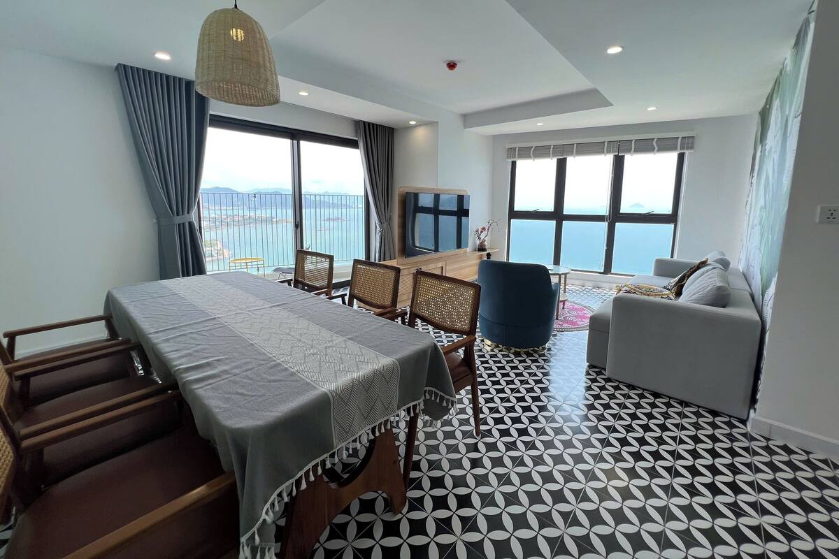 Habitació d'hotel moderna amb un balcó, una zona de dinar i un sofà.