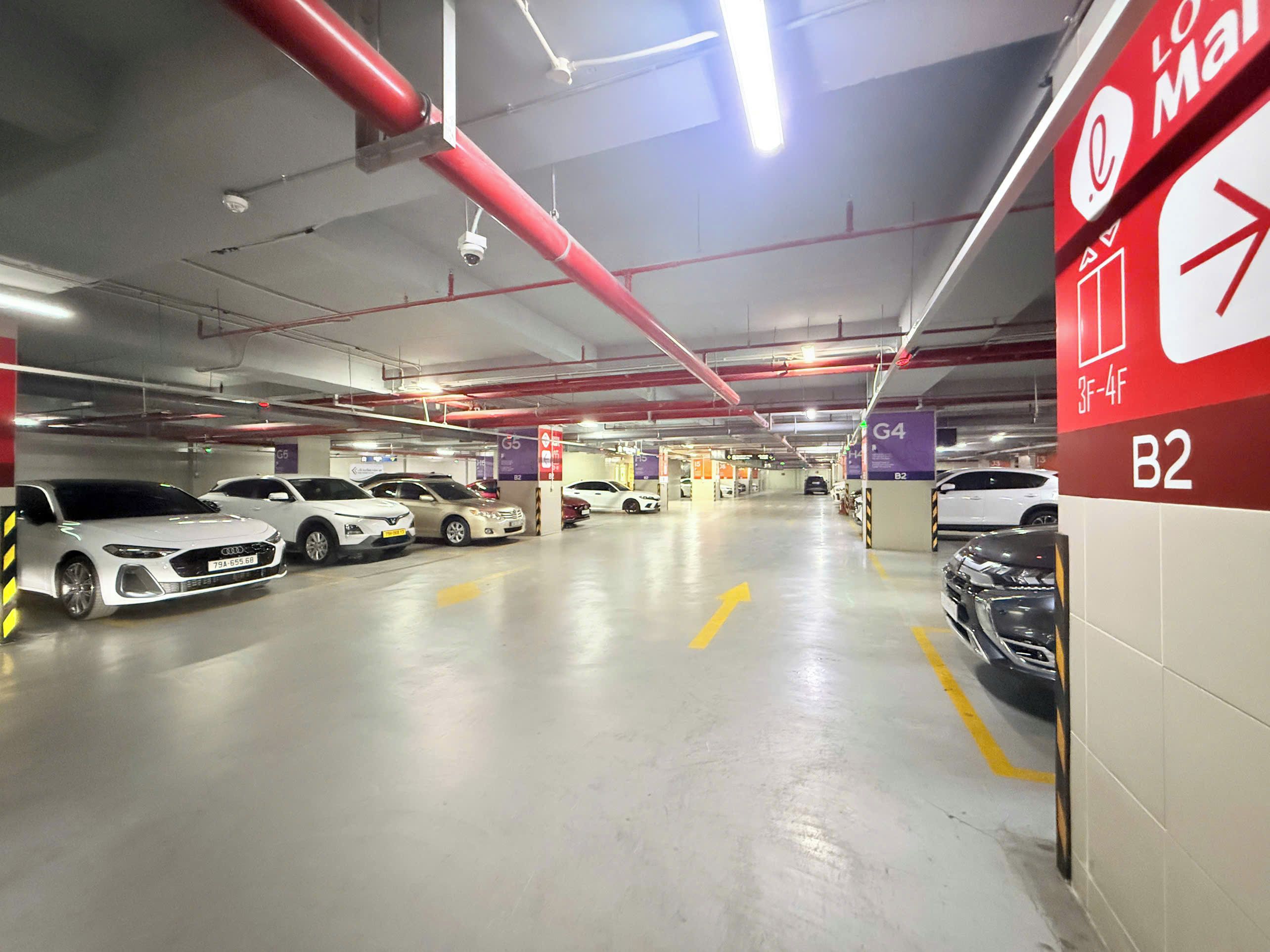 Un parking à plusieurs niveaux, avec des voitures garées dans des emplacements désignés, une signalisation claire indiquant les numéros des emplacements et un panneau de sortie bien visible.