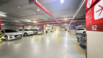 Un parking à plusieurs niveaux, avec des voitures garées dans des emplacements désignés, une signalisation claire indiquant les numéros des emplacements et un panneau de sortie bien visible.