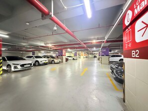 Un estacionamiento de varios niveles con coches estacionados en espacios designados, señalización clara para los números de los espacios y una señal de salida visible.