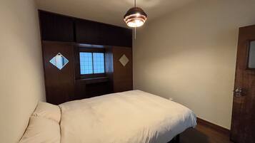 A bedroom with a bed, a window, a wardrobe, and a hanging light fixture.