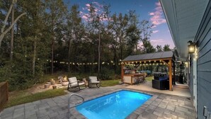 Ein Garten mit Pool, Sitzgelegenheiten im Freien und einer Grillanlage.