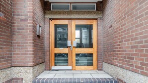 A brick building with a double wooden door, a small window above the door, and a textured ledge above the door. - Blueground | Lambeth, wifi, nr Kennington Park (London)