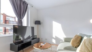 A modern living room with a flat-screen TV, a sofa, a coffee table, and a lamp. - Blueground | Lambeth, wifi, nr Kennington Park (London)