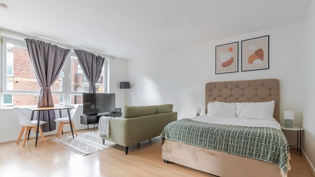A modern hotel room with a bed, a sofa, a desk with a TV, and artwork on the wall. - Blueground | Lambeth, wifi, nr Kennington Park (London)