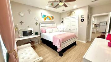 A bedroom with a bed, bedside table, vanity with mirror, and a desk with a computer.