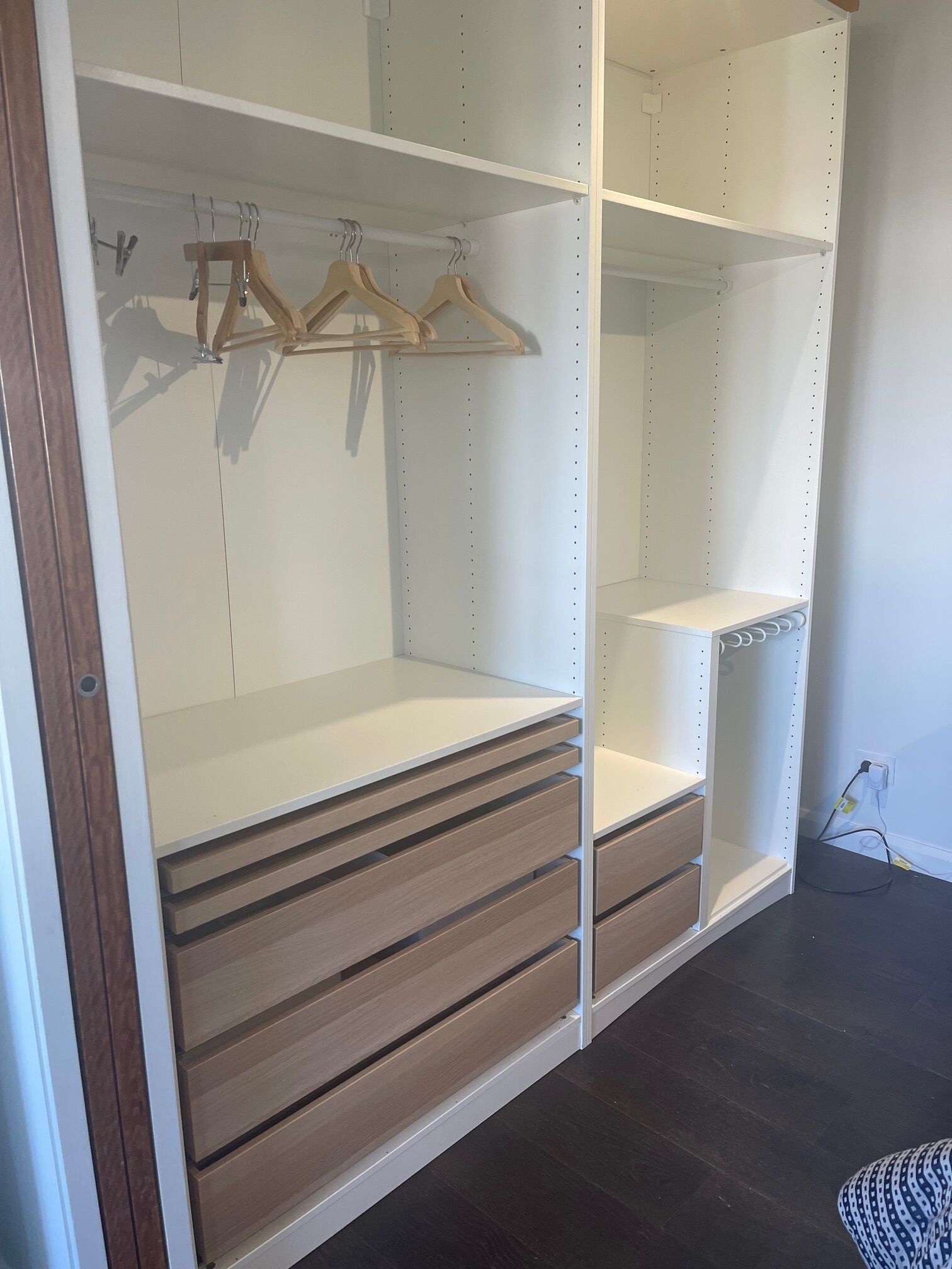 A walk-in closet with open shelves, wooden hangers, and drawers.