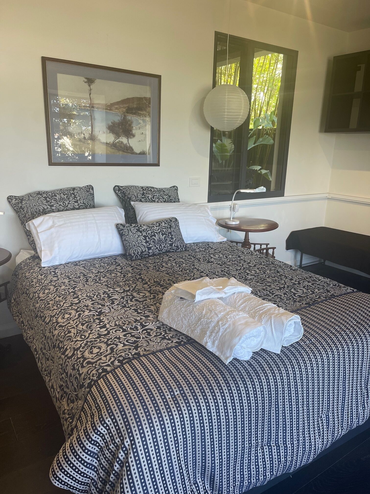 A neatly made bed with patterned bedding, a bedside table, a lamp, and a framed picture on the wall.