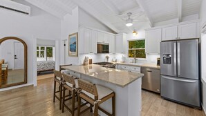 A modern kitchen with white cabinetry, a stainless steel refrigerator, and a bar area with stools. - Private Pool | 2 Mins to Beach | Walk to Dining (St. Thomas)