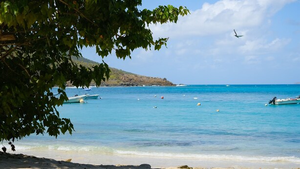 A beach with clear blue water, boats, and a sandy shore. - Private Pool | 2 Mins to Beach | Walk to Dining (St. Thomas)