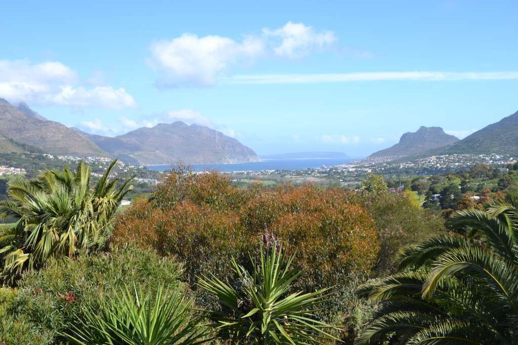 Un paysage côtier avec des montagnes, de la végétation et une vue sur une ville située de l’autre côté de l’eau.