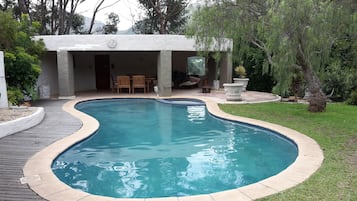 Alberca al aire libre, sombrillas en la alberca y camastros