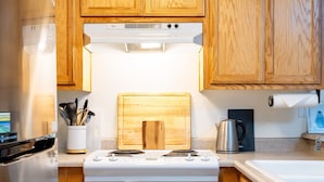 Una cucina con pensili e basi in legno, un fornello, un lavello e una lavastoviglie.