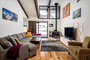 A modern living room with a grey sectional sofa, a patterned armchair, a television, and a fireplace. - New Listing! Cozy Mountain Retreat Near 5-Lakes Hiking Trail & River Rafting, by Tahoe Time VR (Alpine Meadows)