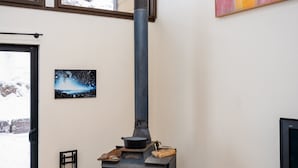 Un soggiorno moderno con stufa a legna, televisore e un quadro astratto dai colori vivaci.