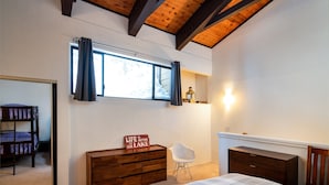 Una camera da letto con un letto a castello, una cassettiera, una sedia, un comodino e una finestra con tende.