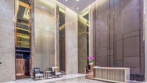 A modern lobby with a reception desk, seating area, and a large glass wall. - Aifte International Apartment (Guangzhou)