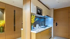 A modern kitchen with a microwave, sink, and cabinets. - Aifte International Apartment (Guangzhou)