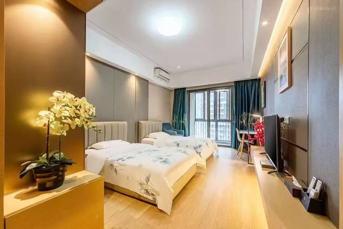 Une chambre d’hôtel avec deux lits, un bureau, une télévision et une grande fenêtre avec des rideaux.