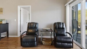 A room with two leather chairs, a small table, and a door leading to another space.