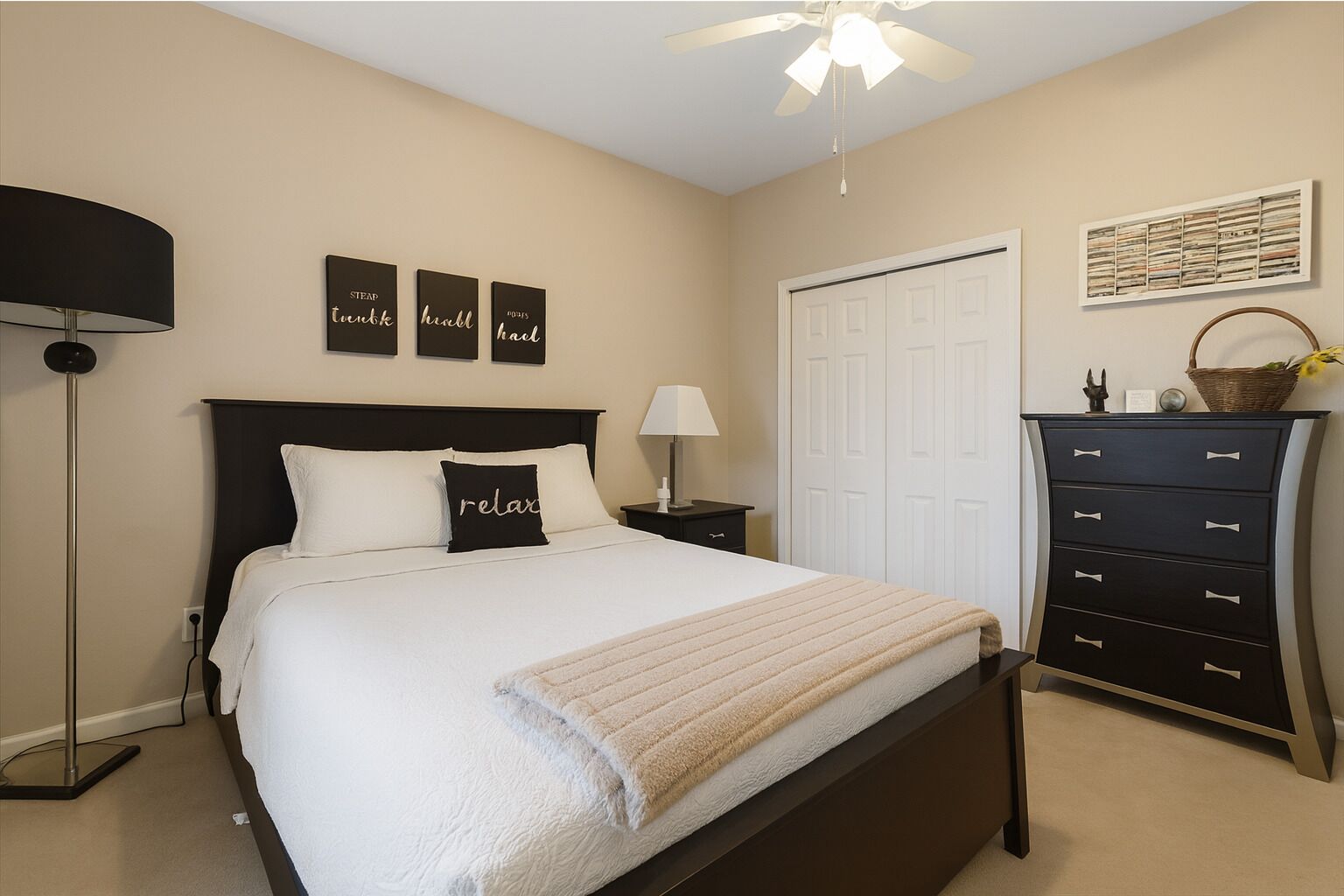 A bedroom with a bed, bedside table, lamp, wardrobe, and wall art.