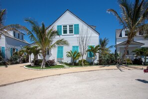 Une maison blanche avec des volets bleus et une pelouse bien entretenue.