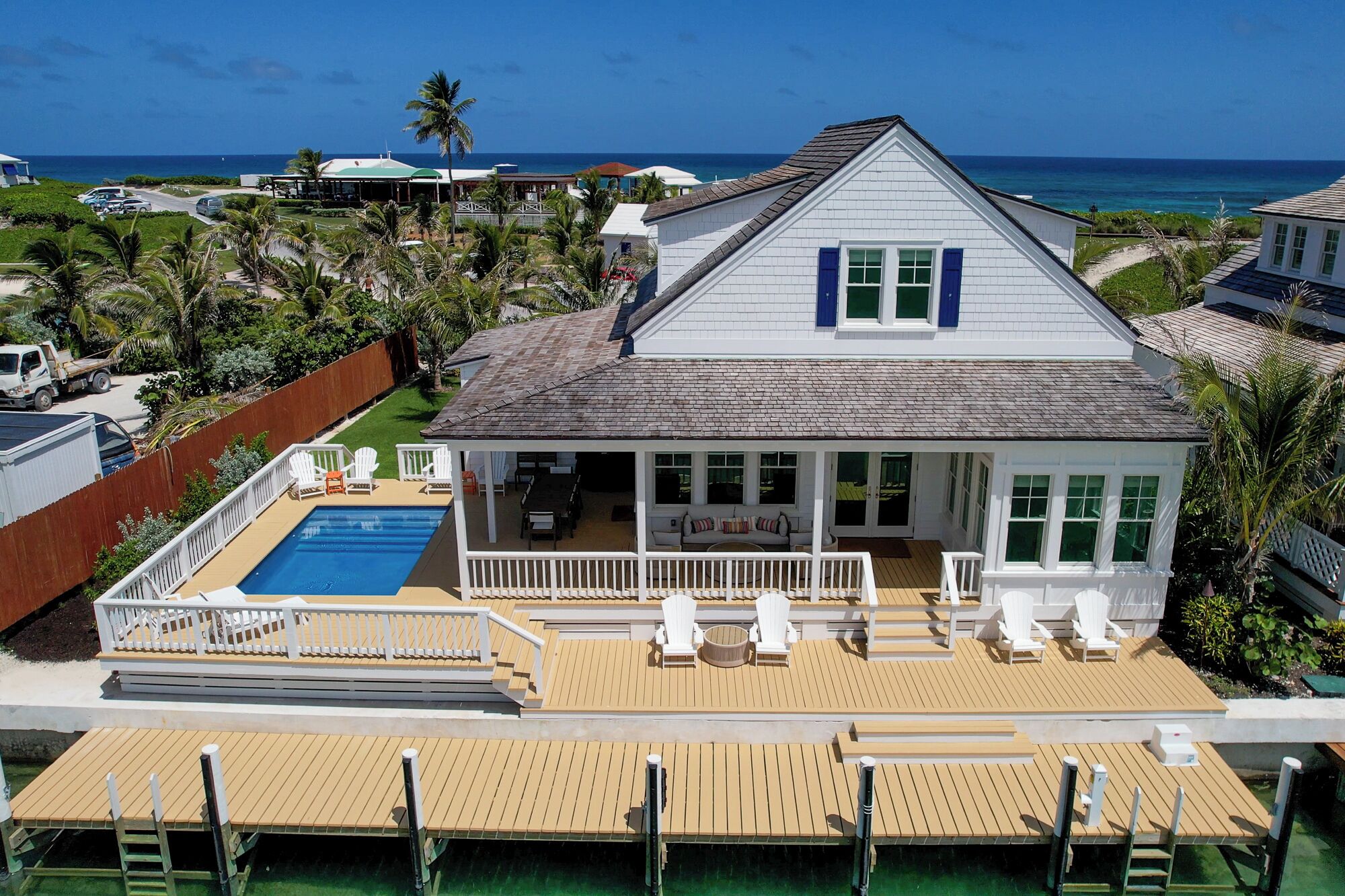 A house with a pool, a covered patio, and a view of the ocean.