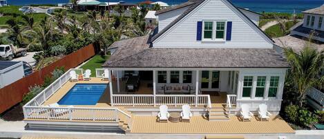 A house with a pool, a covered patio, and a view of the ocean.