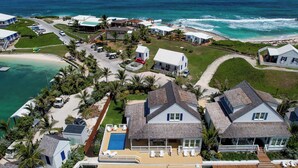 A coastal property with two main houses, a swimming pool, and a dock extending into the water. - South End Villa on the Water: Lovely Pool, Expansive Decks, and 60’ Private Dock (Elbow cay)