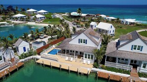 A coastal resort with multiple villas, a central pool, and a pier extending into the water. - South End Villa on the Water: Lovely Pool, Expansive Decks, and 60’ Private Dock (Elbow cay)