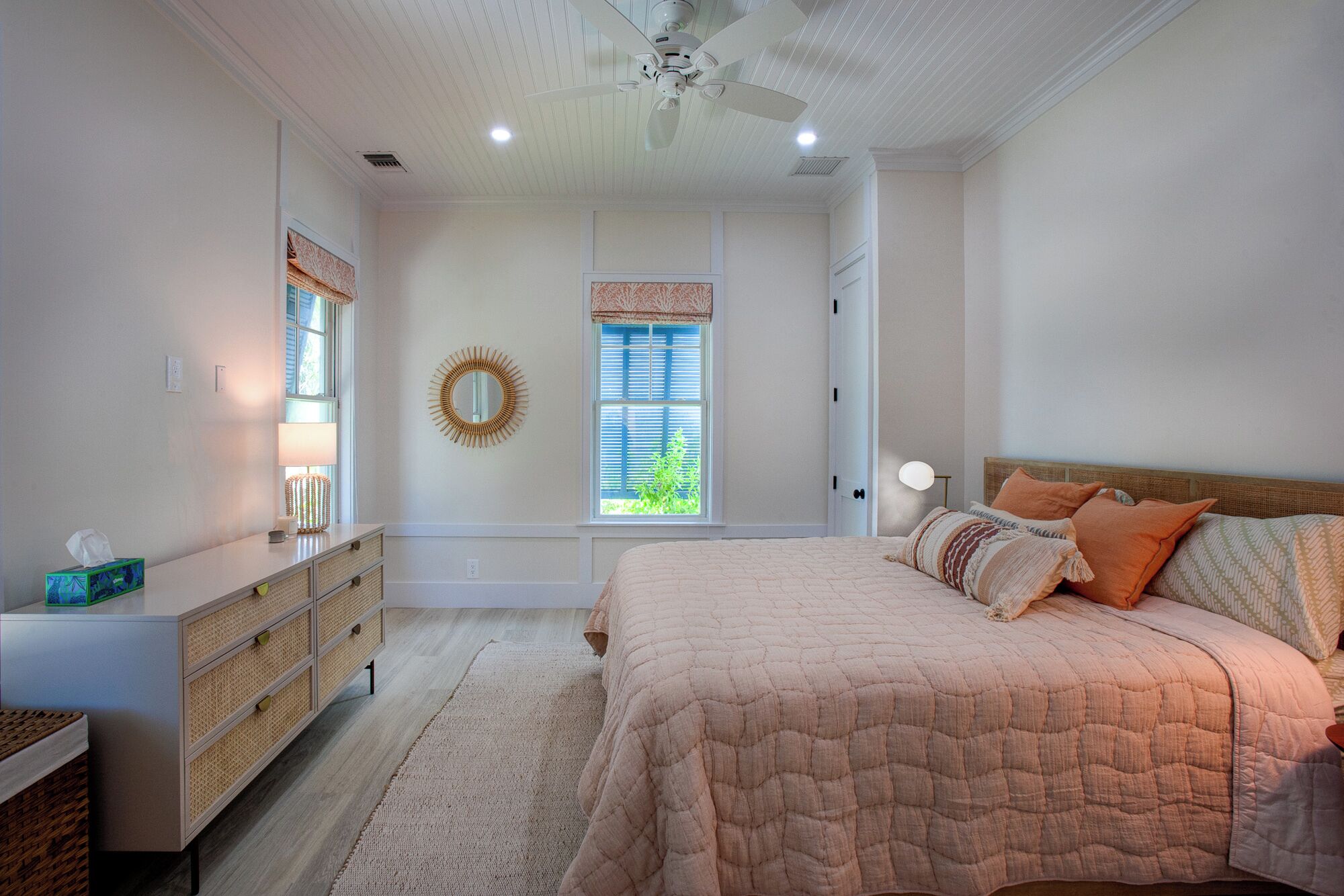 A bedroom with a bed, dresser, and a ceiling fan.