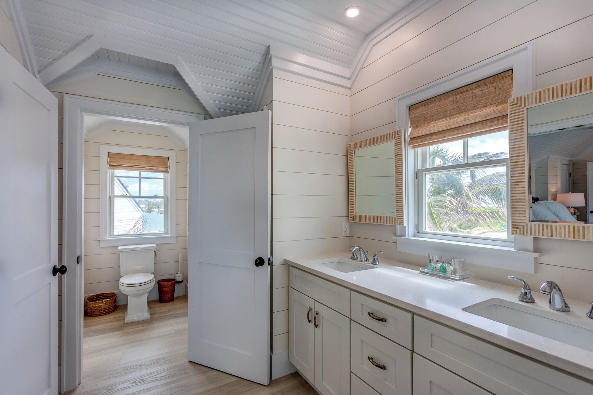 A bathroom with a large window, a sink, and a toilet.