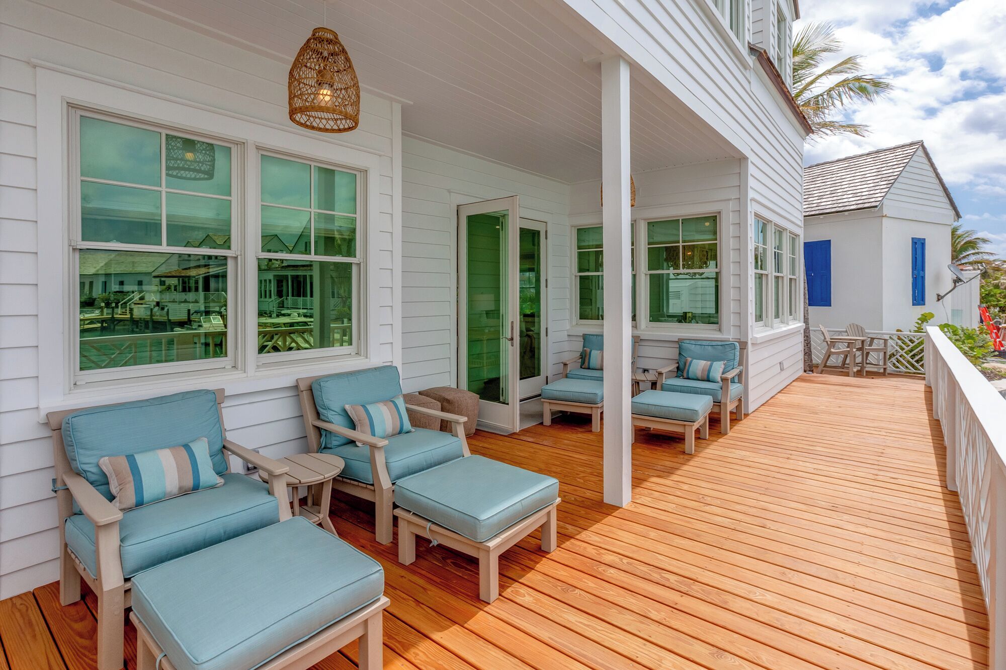 A covered porch with light blue cushioned chairs and a wooden deck.