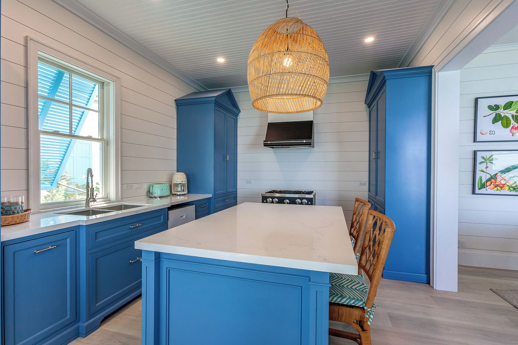 A kitchen with blue cabinets, a white island, a gas stove, and a hanging light fixture.