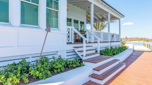 A white building with a covered porch, steps leading to the porch, and a wooden deck. - Ocean View Cottage at Abaco Inn (Elbow cay)