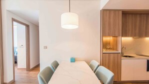 Une cuisine moderne avec des meubles en bois, un plan de travail en marbre et un luminaire suspendu.