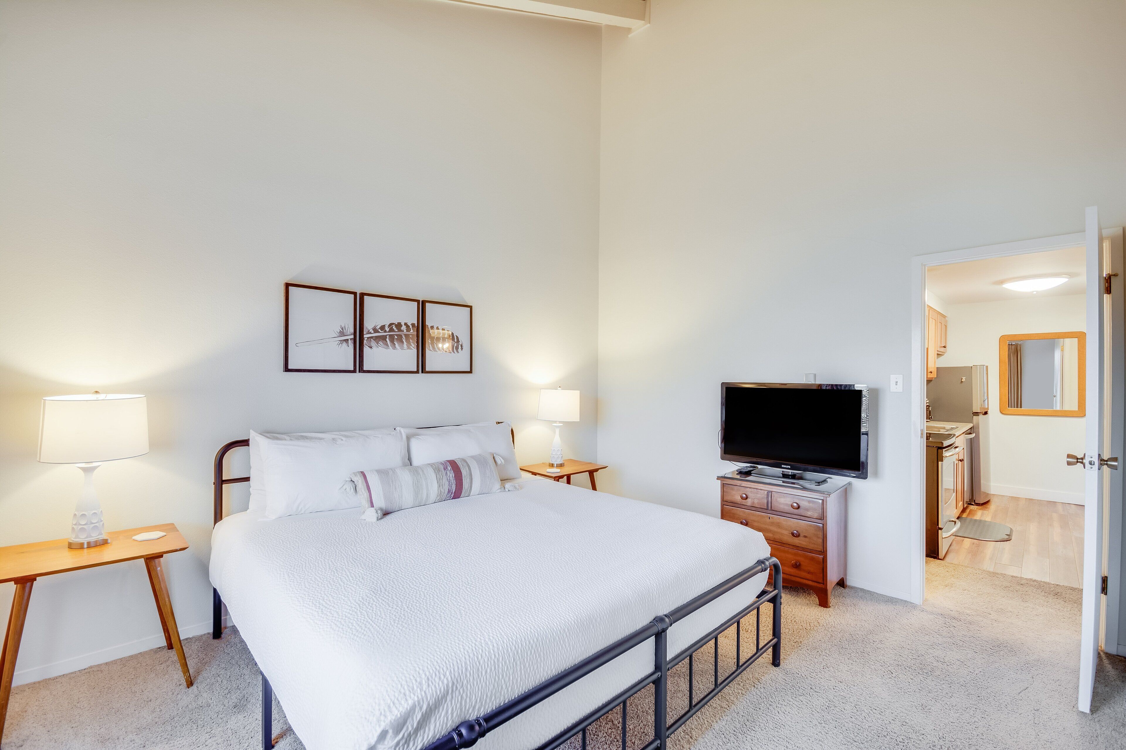 A bedroom with a bed, bedside tables, a TV, and a bathroom visible through an open door.