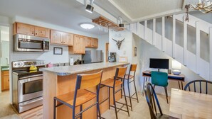 Eine moderne Küche mit Holzausbau, einem Edelstahlherd und einer Bar mit Barhocker.