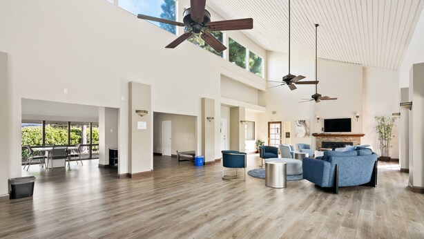 Un vaste espace intérieur doté d’un haut plafond, de plusieurs ventilateurs de plafond et d’un grand coin salon avec des canapés bleus.
