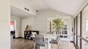 Un espace repas moderne avec une table blanche, des chaises grises et une bibliothèque.