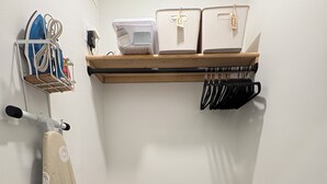 Un cuarto de lavado con tendedero, tabla de planchar y ropa colgada en un estante.