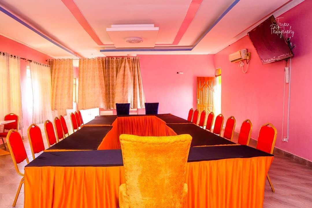 A conference room with a long table, red chairs, and a yellow chair in the foreground.