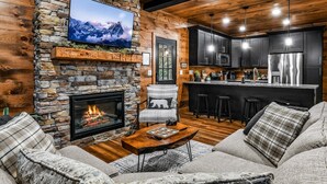 A cozy living room with a stone fireplace, a flat-screen TV, and a comfortable seating area. - Pearl's Mountain Retreat: Wifi, Hot Tub, Free Attraction Tickets, & Game Room (Sevierville)